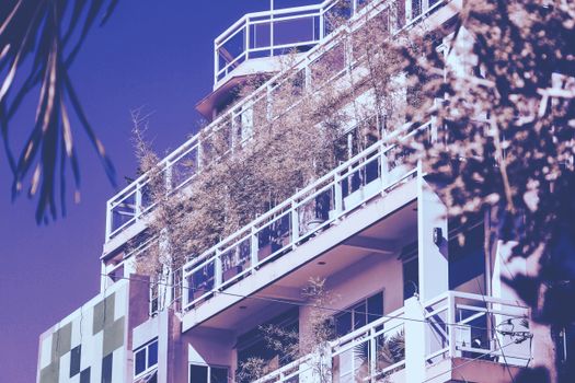 A modern multi-story building in the Philippines featuring greenery on balconies.