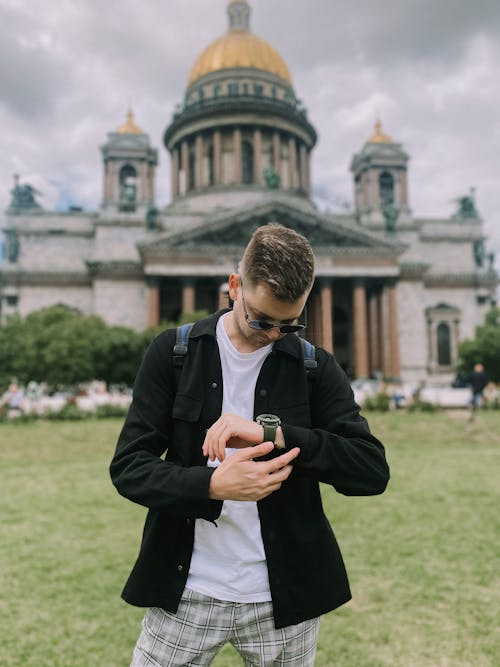 Man in White Shirt and Black Jacket Looking at His Watch in Front of Saint Isaac's Cathedral 