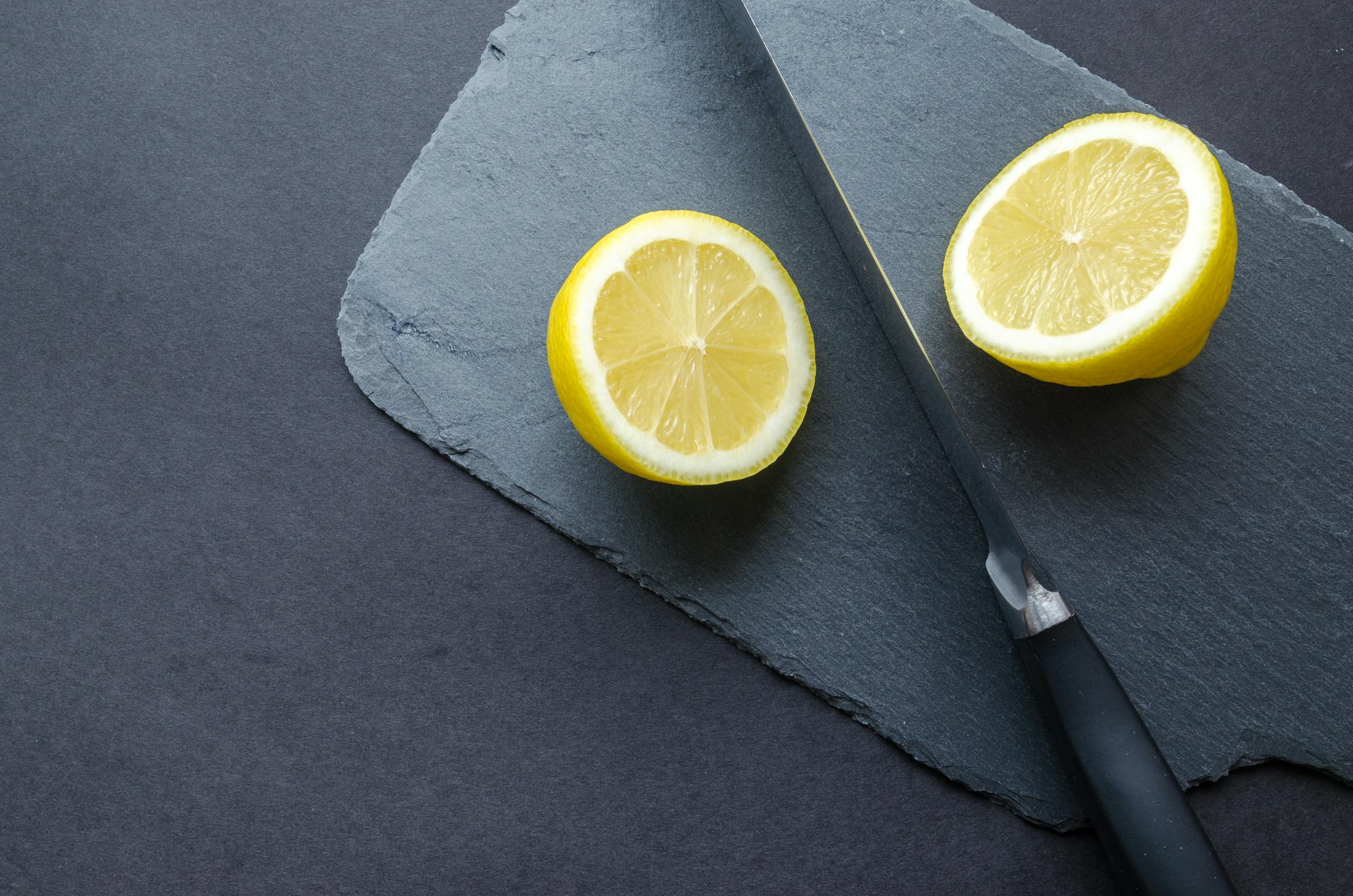 sliced lemon on gray surface with a knife