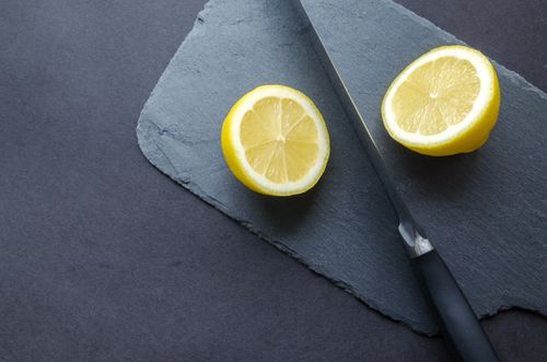 Free Close-up of lemon halves with knife on slate board, highlighting freshness and vibrant colors. Stock Photo