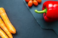 石板表面色彩斑斓地排列着新鲜的胡萝卜、西红柿和甜椒