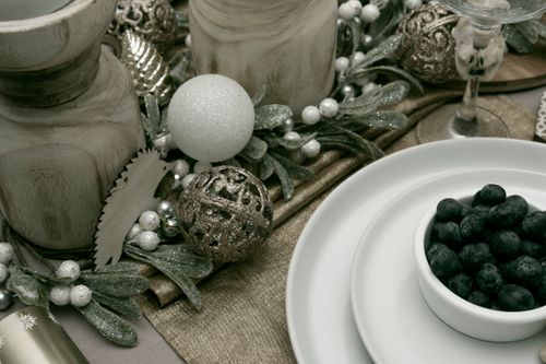 Free A sophisticated holiday table setting featuring a bowl of blackberries, decorative ornaments, and natural elements. Stock Photo