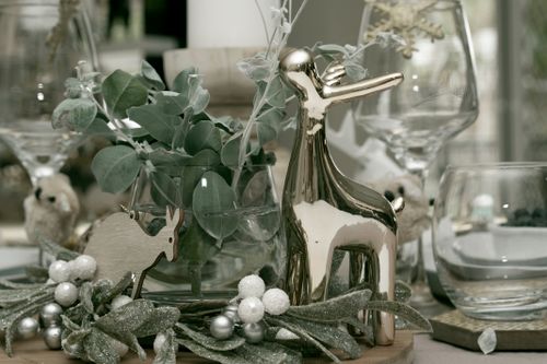 Free Stylish winter table setting featuring a metallic deer figurine and greenery. Stock Photo