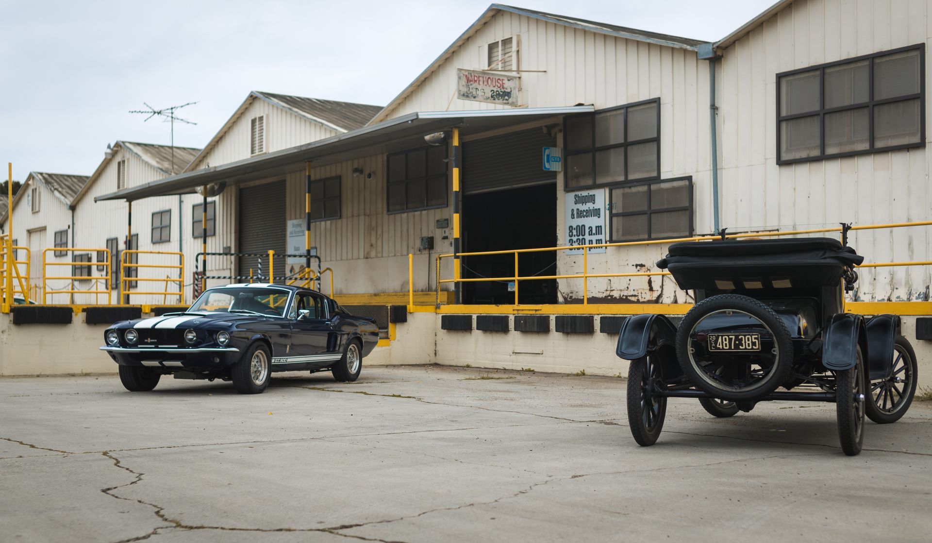 Vintage and classic cars parked outside an urban warehouse in Los Angeles, California.
