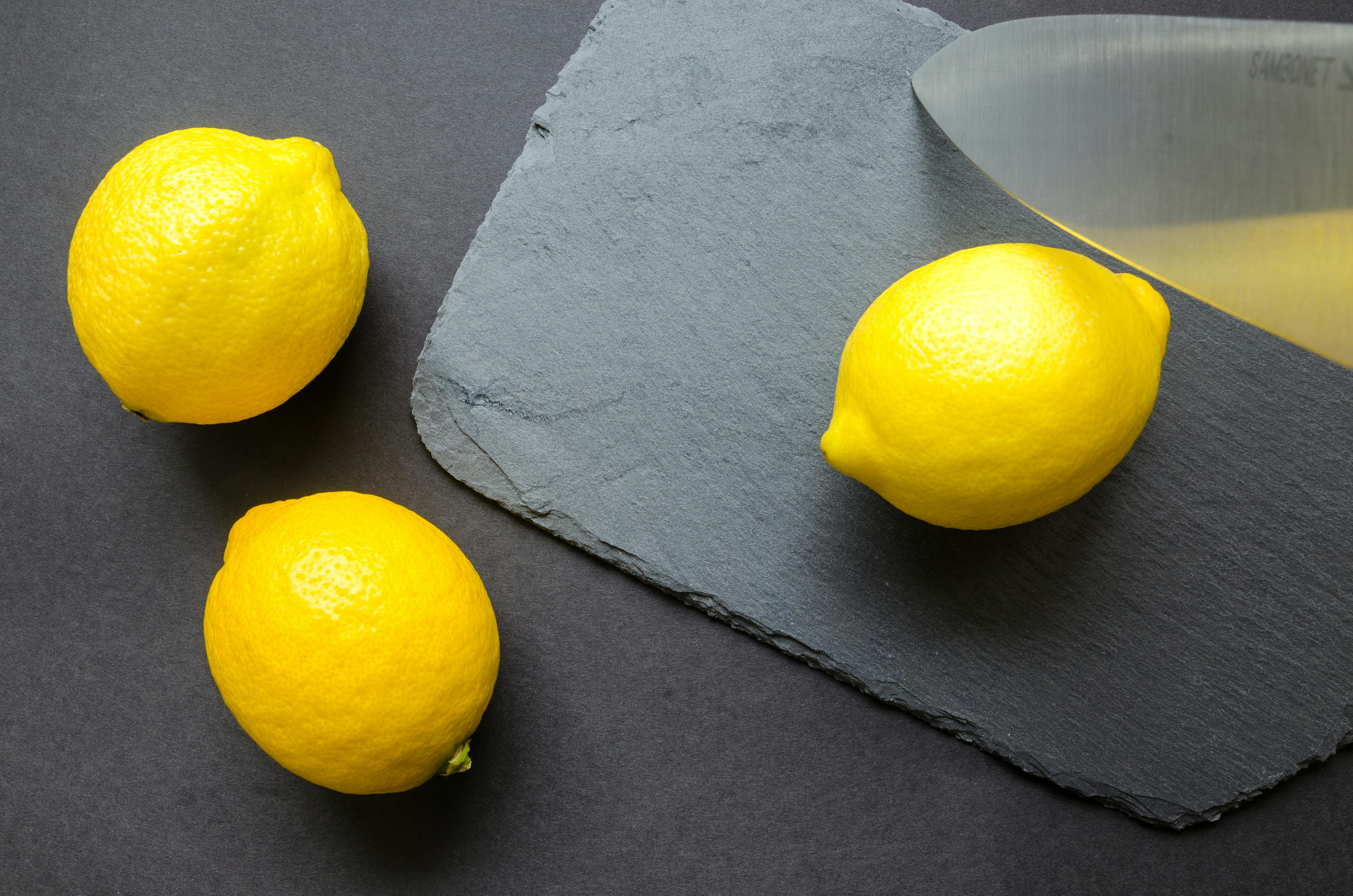 three lemons on grey surface