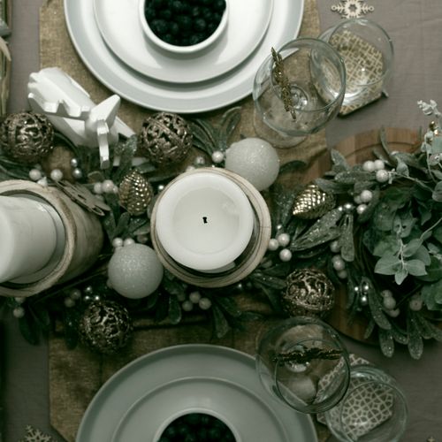 Free A top view of an elegant Christmas table setting featuring a candle centerpiece, ornaments, and dishware. Stock Photo