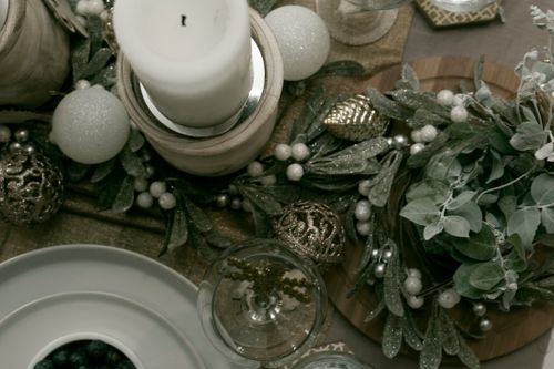 Free A festive holiday table setting featuring a candle and decorative arrangement with ornaments and greenery. Stock Photo