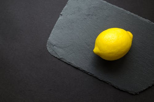 Фотография желтого лимона на серой поверхности