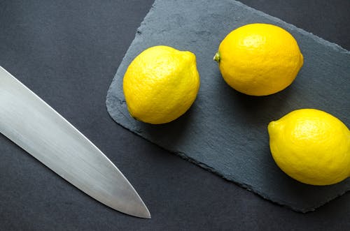 Photo of Three Lemons on Chopping Board Near Knife