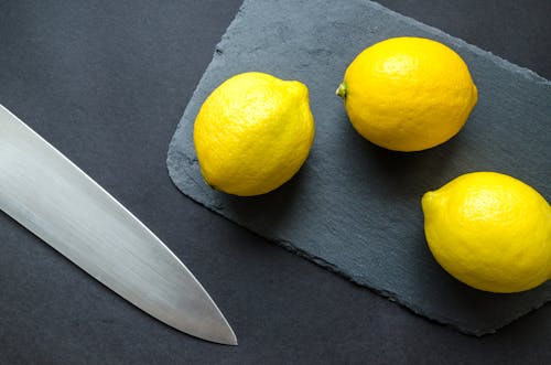 Foto De Tres Limones En Una Tabla De Cortar Cerca De Un Cuchillo