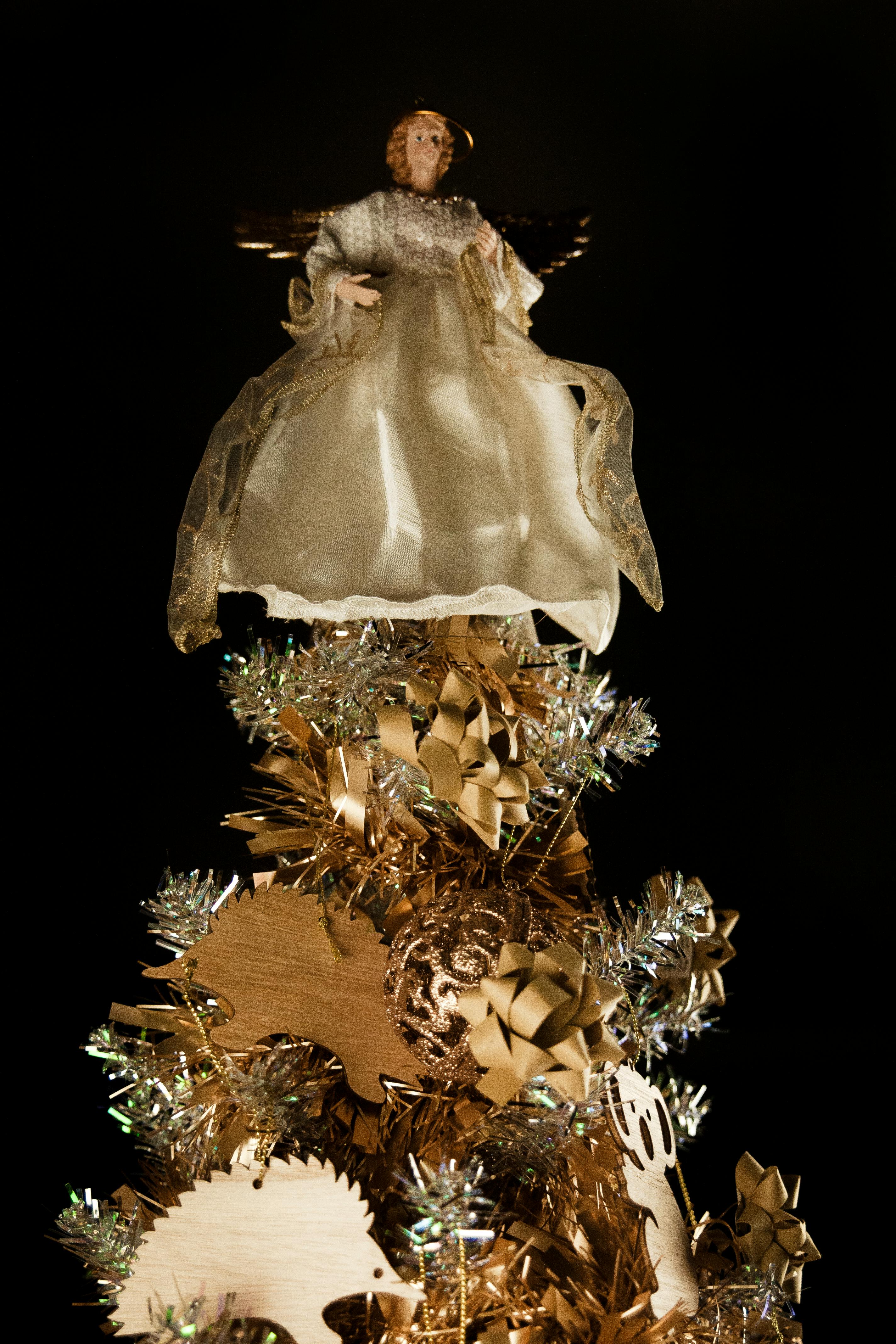 An Angel Figurine on Top of a Gold and Silver Themed Christmas Tree