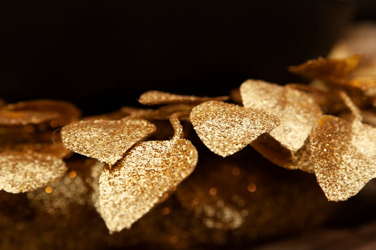 A Christmas Ornament Of Leaves With Gold Glitters