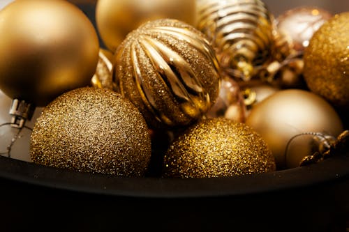 A Bucket of Gold Christmas Baubles in Close-up Photography