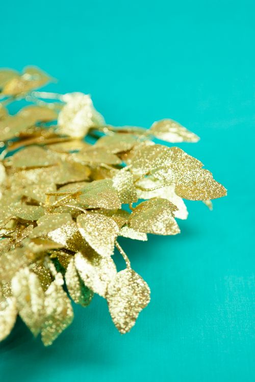 Free Shimmering golden leaves decorate a vibrant teal backdrop, perfect for festive themes. Stock Photo