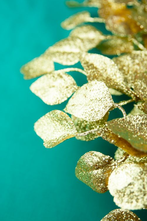 Free Close-up of decorative golden leaves with glitter on a vibrant green background. Stock Photo
