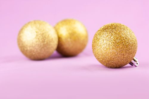 Free Close-up of glittering gold Christmas ornament balls on a vibrant pink surface. Stock Photo