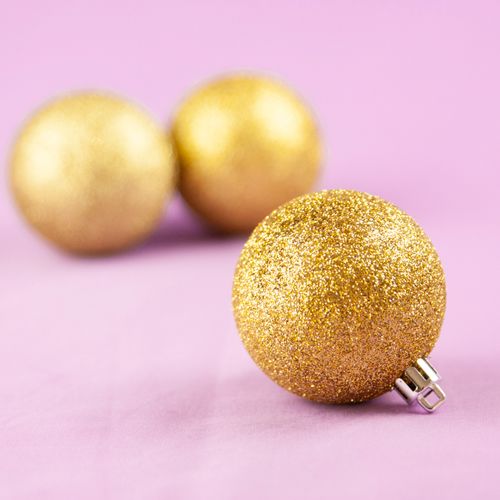 Free Close-up of golden glittering Christmas ornaments on a soft pink background. Stock Photo
