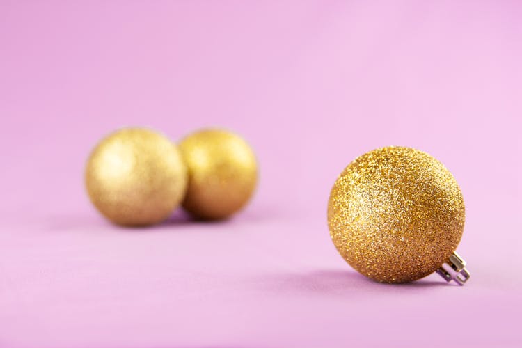 Gold Christmas Balls Over A Purple Surface