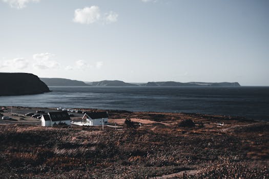 Panoramic view of a coastal landscape featuring buildings and ocean, set under a clear sky.