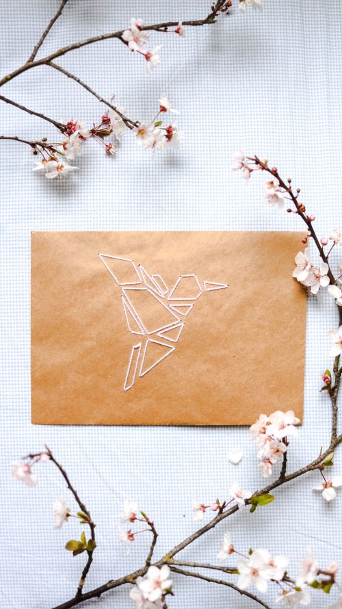 Free A top view of an origami bird on paper surrounded by cherry blossoms, evoking spring. Stock Photo