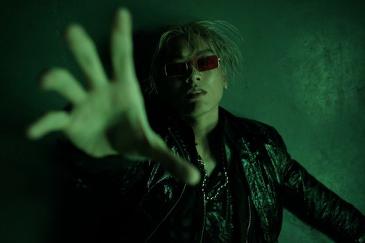 A modern and futuristic portrait of a man posing indoors with a green lighting effect.