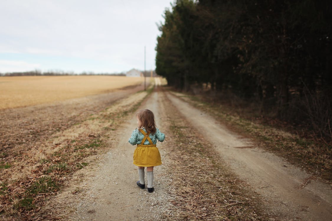 Free Girl Wearing Blue Long-sleeved Shirt and Yellow Skirt Walking on Pathway Stock Photo