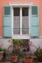 Window with green shutters on peach colored house in Paris