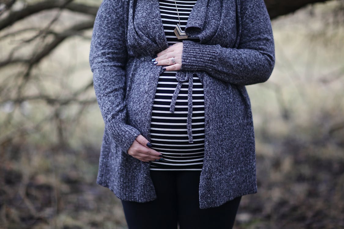 Free Woman Pregnant in Black and White Striped Shirt Standing Near Bare Tree Stock Photo