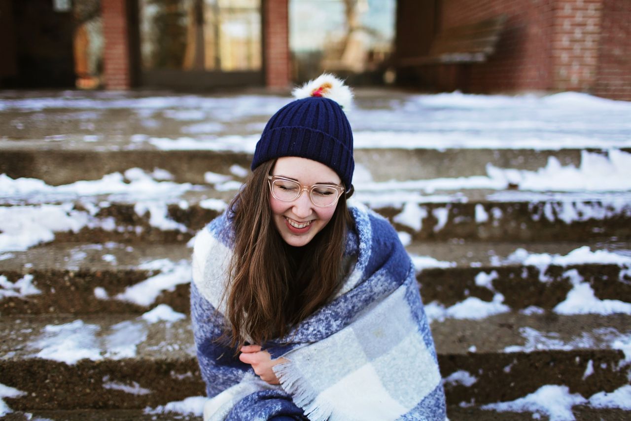 Woman in a blue and white shawl sitting on snowy steps in winter