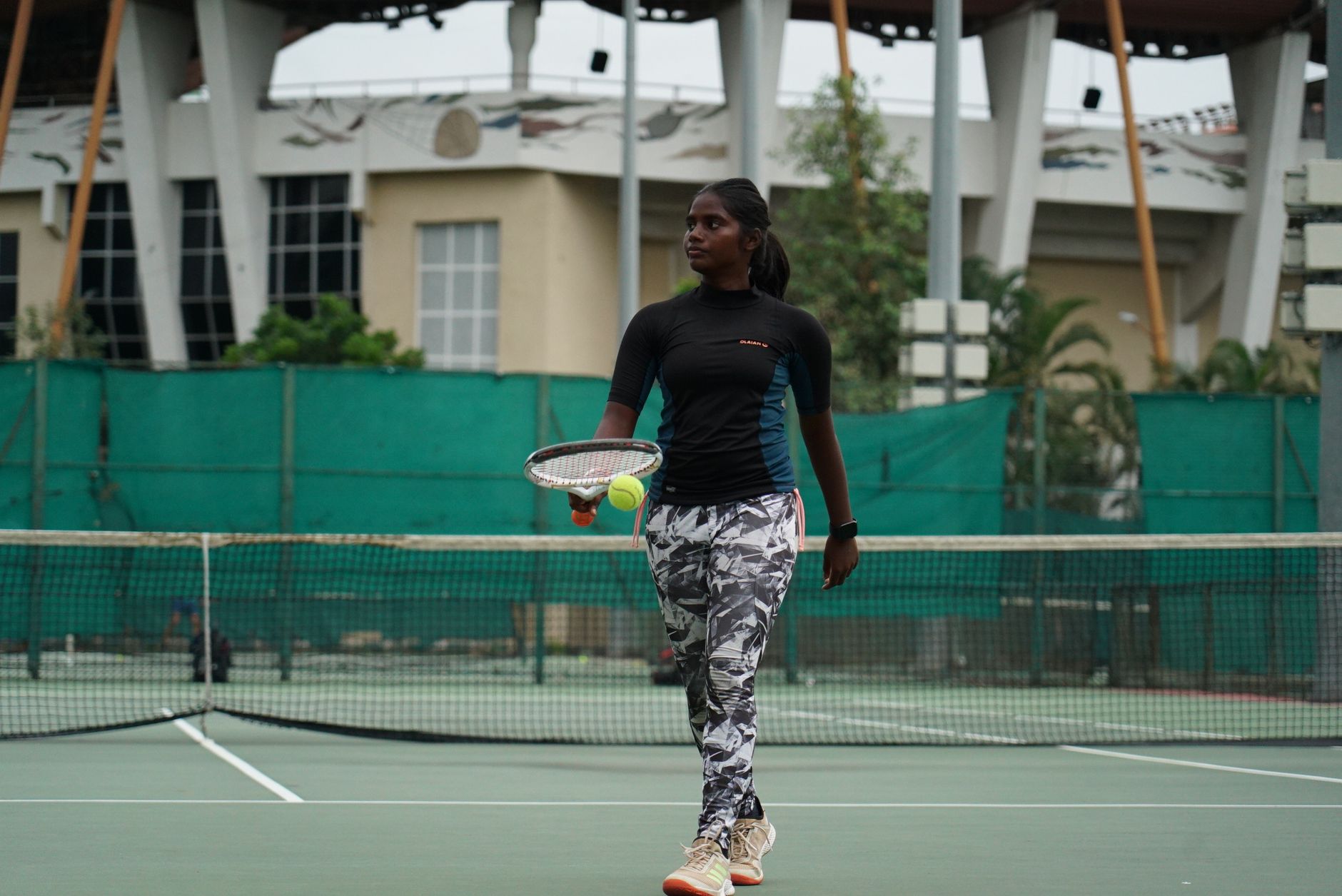 A focused young athlete practicing tennis on an outdoor court, ready to serve the ball.