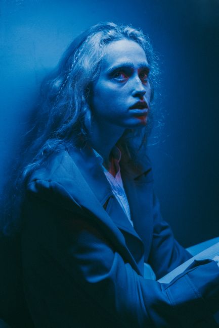 Artistic portrait of a woman in dramatic blue lighting, looking introspective.