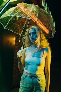 A woman standing outdoors at night holding an umbrella under neon lights.