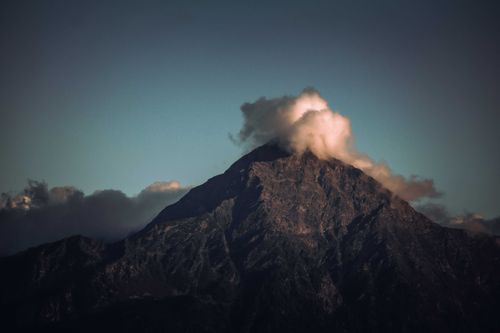 Free A stunning view of a mountain peak covered by clouds against a dark sky, capturing the essence of nature's majesty. Stock Photo