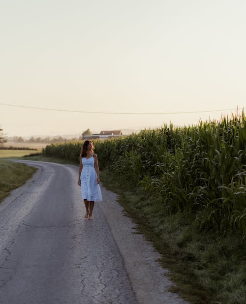 Free Woman in White Dress Walking on Road Admiring the Scenery Stock Photo