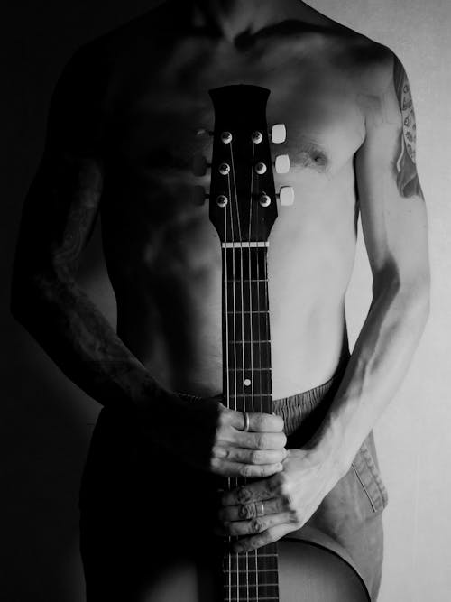 A Topless Man Holding a Guitar