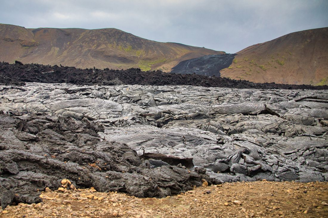 Cooled lava field below ridged hills — photo by Koen Swiers on Pexels