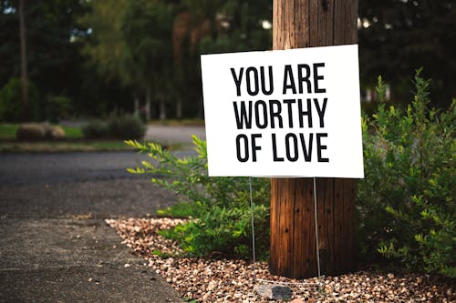 免费 您值得在棕色木制帖子上贴上爱情标牌 素材图片