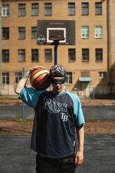 Teenager with a basketball in an urban outdoor setting, showcasing street style.