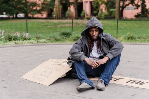 Free A homeless man in a city park sitting with a cardboard sign seeking help. Stock Photo