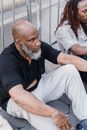 Man in Black Polo Shirt Sitting Beside Man in White Pants