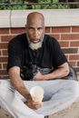Man in Black Crew Neck T-shirt and Gray Pants Sitting on Brown Wooden Bench