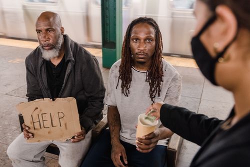 Free A person gives assistance to two homeless men in a subway station. Stock Photo
