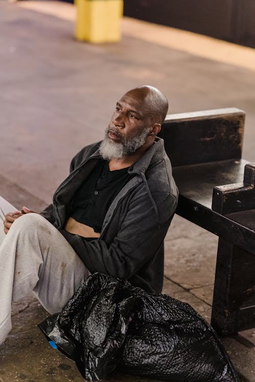 Man in Black Jacket Sitting on Brown Wooden Bench