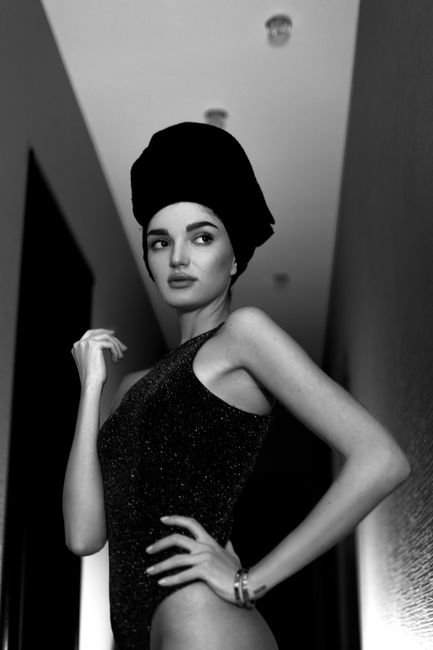 Striking black-and-white portrait of a model posing in a hallway.