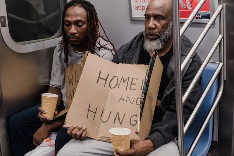 Men In A Subway With Cardboard Banners 