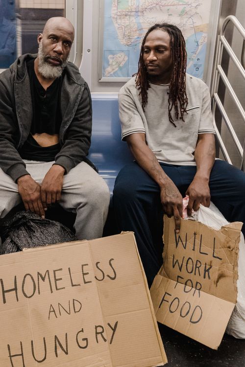Free A candid portrait of two homeless men with signs on public transportation. Stock Photo