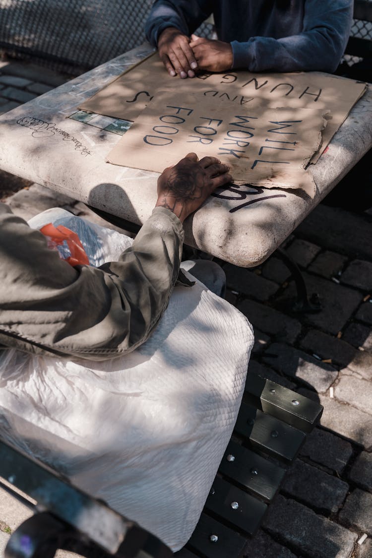 Men Sitting At A Table In City With Cardboard Banners 