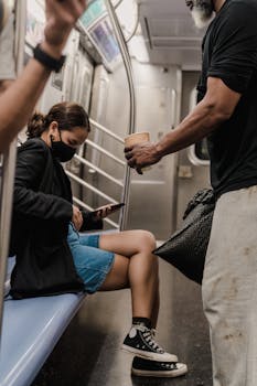 A woman on a train using her cellphone, wearing a face mask, illustrating urban commuting.