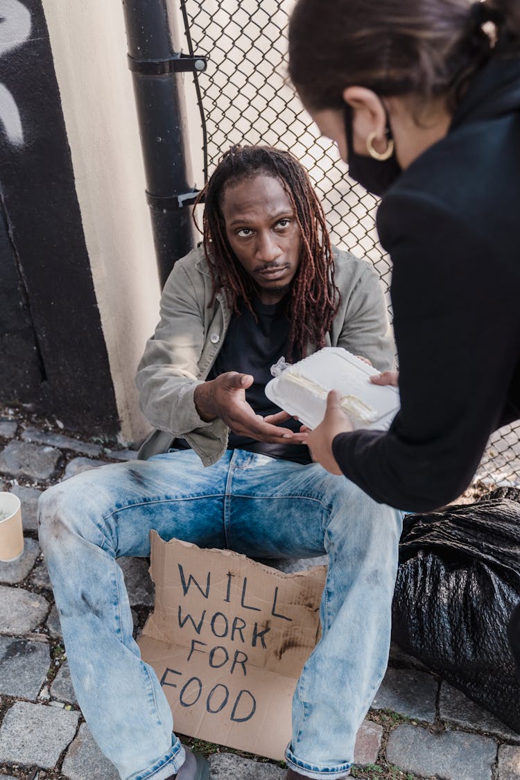 Woman Giving Food On Homeless Man 