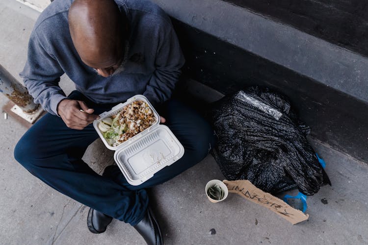 Man Sitting On The Ground Eating